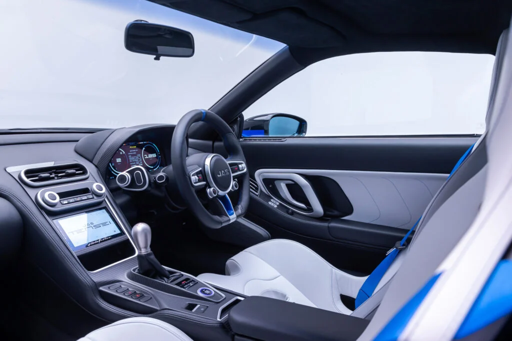 Right-hand-drive JAS Tensei interior with a three-spoke steering wheel, digital instruments, an exposed manual gearlever and pale leather seats