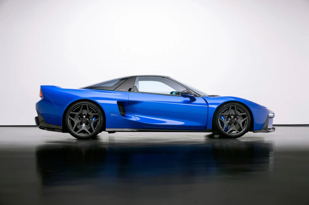 Side profile of a blue JAS Tensei in a white studio, showing its low beltline, slim glasshouse, side air intake and centre-lock wheels