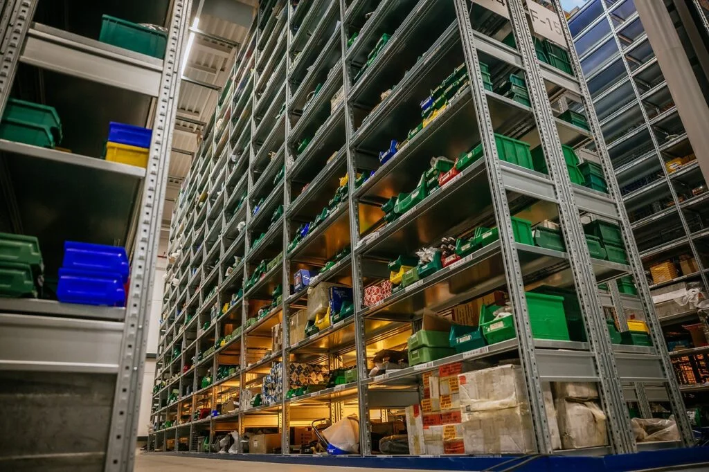 Tall shelving filled with green and blue crates of spare parts in the Mercedes-Benz Classic Center parts store
